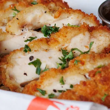 Close-up irisan dada ayam crispy, lapisan tepung keemasan dan dalamnya juicy